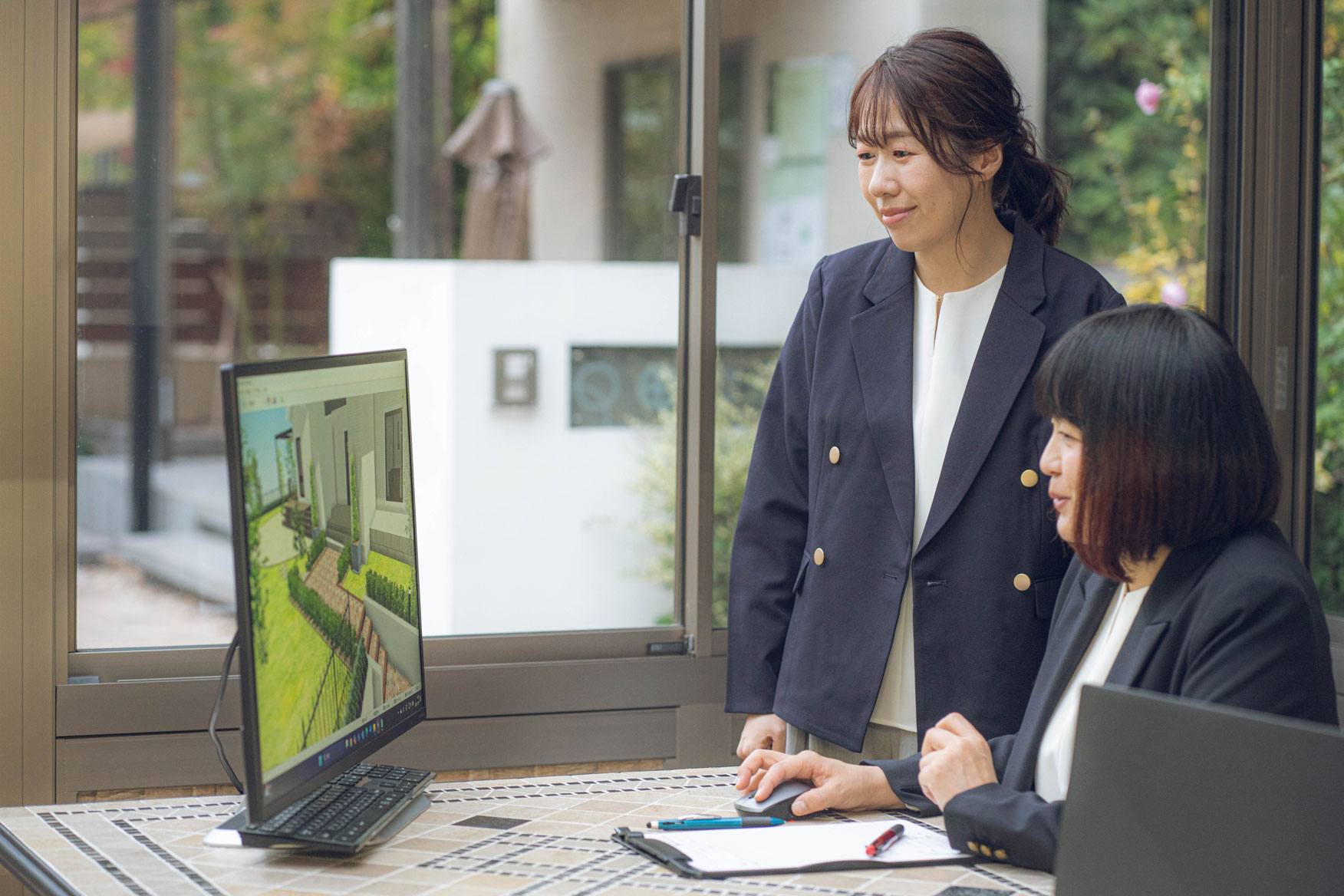 屋外でパソコンのモニターを見る二人の女性