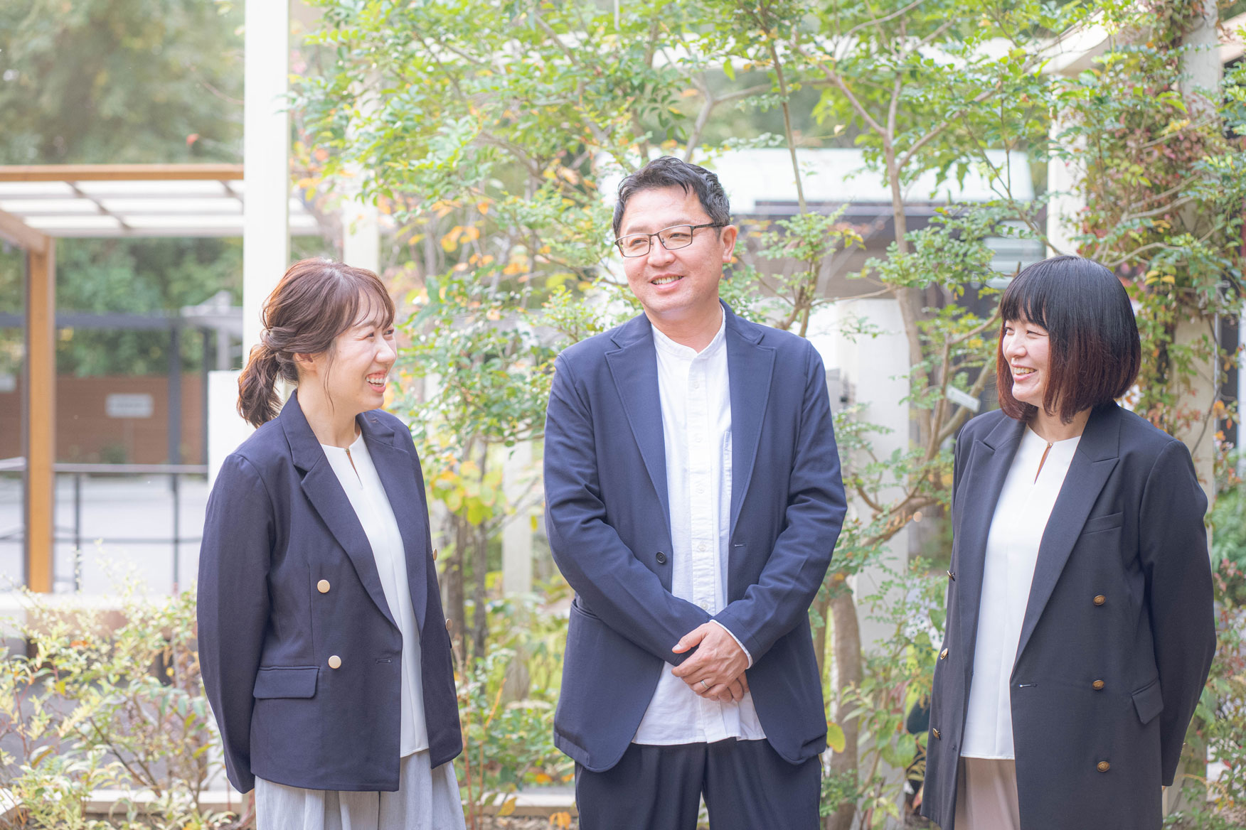 男性と二人の女性が笑顔で会話している様子